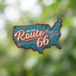 May include: A teal embroidered patch shaped like the map of the United States. The text reads Route 66, 1926-2026, and 100 years in white script and block lettering with orange outlines. Two small orange stars are positioned on the map surface.
