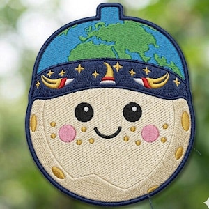 May include: Embroidered patch featuring a smiling moon with rosy cheeks, wearing a blue hat with stars and a globe on top. The moon has a cream-colored face with gold accents and a black smiling mouth.