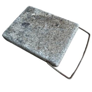 May include: A gray stone slab with a metal handle. The stone is rough and textured. The handle is attached to the slab with a metal loop.