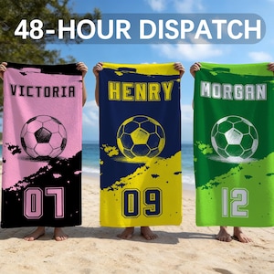 Puede incluir: Tres toallas de fútbol personalizadas en rosa, azul marino y verde. Cada toalla presenta un gráfico de balón de fútbol, un nombre y un número. Las toallas se sostienen en una playa con el texto "48-HOUR DISPATCH" en el fondo.