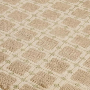 May include: A beige rug with a repeating geometric pattern of squares and diamonds. The squares are a darker beige color, outlined in a lighter beige, and the diamonds are a light green color.