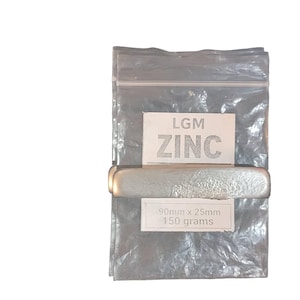 May include: A silver zinc bar, labelled "LGM ZINC", is contained within a clear plastic bag. The label also states dimensions of 90mm x 25mm and a weight of 150 grams. The bar is rectangular with rounded edges.