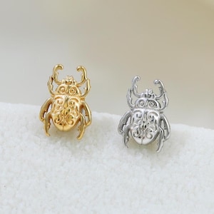 May include: A white ceramic mug with a black handle and the text "But First, Coffee" in a black, handwritten-style font. The mug is on a white surface.