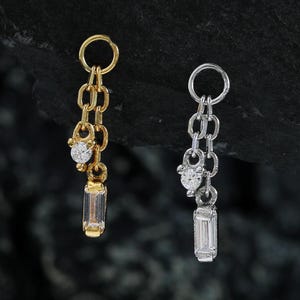May include: Two dangling earrings, one gold-toned and one silver-toned, each featuring a chain design. The gold earring has a small round diamond and a rectangular stone. The silver earring has a similar design.