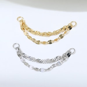 May include: Two double-strand jewelry connectors, one in gold tone and one in silver tone. Each piece features a twisted chain and a flat, oval-link chain attached to a small circular jump ring at each end for secure attachment to jewelry.