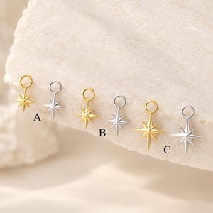 May include: Six star-shaped charms arranged in pairs, featuring gold and silver tones. Each charm has a circular jump ring at the top and a multi-pointed star design. The pairs are labelled A, B, and C, showcasing variations in size and finish.