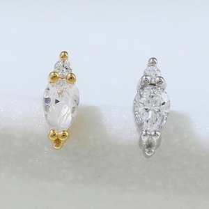 May include: Two stud earrings. One is gold-toned with a pear-shaped clear stone and small clear stones. The other is silver-toned with a pear-shaped clear stone and small clear stones. Both earrings are on a white surface.