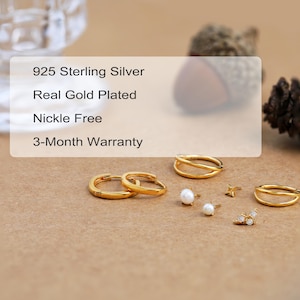 May include: A collection of gold-plated 925 sterling silver jewelry including two hoop earrings, two double-band rings, two pearl stud earrings, a small star-shaped stud, and a small bee-shaped stud with clear stones. Text reads 925 Sterling Silver.
