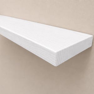 May include: A rectangular floating wall shelf with a bright white finish and a visible wood grain texture. The shelf features clean, straight edges and a smooth surface, extending horizontally from the wall with a solid, sturdy construction.