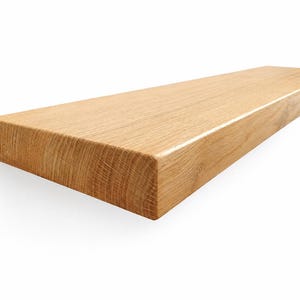 Peut inclure: Une étagère flottante rectangulaire en bois de chêne clair massif avec un motif de grain naturel visible. L'étagère présente une surface lisse et finie ainsi que des bords droits et nets, mettant en valeur la texture organique du bois.