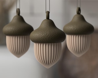 May include: Three hanging acorn ornaments featuring textured dark olive green caps and smooth, vertically ribbed light beige bodies. Each ornament includes a small loop at the top for suspension, showcasing a consistent design and neutral color palette.