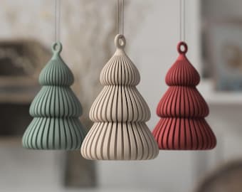May include: Three hanging ornaments shaped like stylized Christmas trees with a ribbed, vertical texture. The ornaments are colored in muted sage green, beige, and deep red, each featuring a small circular loop at the top for hanging by a thin string.