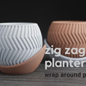 May include: Two decorative planters with a zig-zag pattern. One is light grey, the other is terracotta. Both sit on a matching wrap-around plate. The text "zig zag planter" and "wrap around plate" is visible.