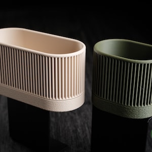 以下が含まれることがあります： 黒いハンドルと「But First, Coffee」のテキストが黒い太字で書かれた白いセラミックマグ。マグは木製の表面に置かれています。マグの高さは約10cmです。