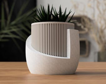 May include: A modern, two-tone planter with a cylindrical, slatted upper section and a curved, solid base. The planter holds a dark green succulent plant. The design features a neutral color palette, suitable for various interior styles.