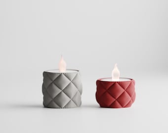 May include: Two decorative LED candles. One is gray, the other is red. Both have a quilted pattern around the base and a flickering flame effect. The candles are designed to resemble small, modern lanterns.