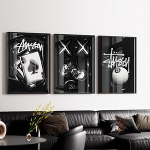 May include: A set of three black framed wall art prints featuring monochromatic graphics. The first print shows an ace of spades playing card with the Stussy logo. The second displays two X shapes and a hand holding cash. The third shows an 8 ball.