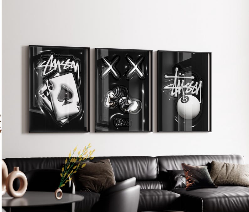 May include: A set of three black framed wall art prints featuring monochromatic graphics. The first print shows an ace of spades playing card with the Stussy logo. The second displays two X shapes and a hand holding cash. The third shows an 8 ball.