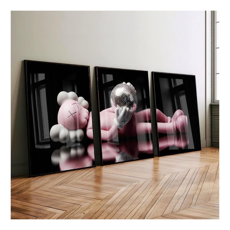 May include: Three framed art prints featuring a pink figure with a disco ball head and white gloves. The figure is lying down in a reflective black space. The other print shows a pink figure with white gloves and a cloud-like head. The frames are black.