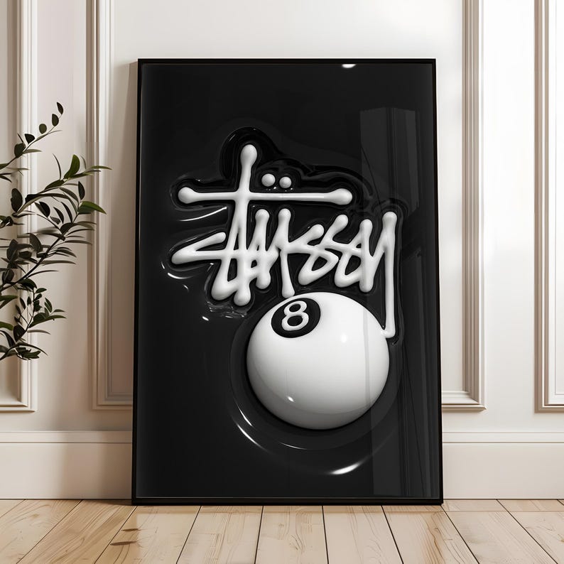 May include: A rectangular framed wall art piece featuring a glossy black background with a raised, three-dimensional white St&uuml;ssy logo script positioned above a large, white billiard ball with a black number eight centered on its surface.