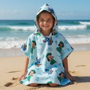 May include: A light blue hooded poncho towel featuring an all-over print of the character Stitch playing a ukulele and a character wearing a green hula skirt, interspersed with small palm tree and seashell illustrations across the fabric.