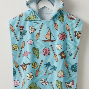 May include: A light blue hooded towel poncho featuring a repeating pattern of tropical motifs including wooden oars, sailboats, palm trees, hibiscus flowers, seashells, green leaves, a rooster, a pig, and small island landscapes with a wavy background.