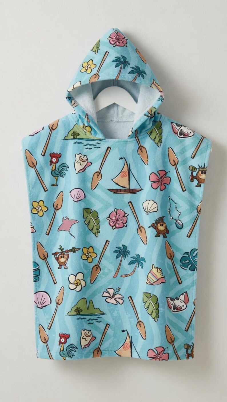 May include: A light blue hooded towel poncho featuring a repeating pattern of tropical motifs including wooden oars, sailboats, palm trees, hibiscus flowers, seashells, green leaves, a rooster, a pig, and small island landscapes with a wavy background.