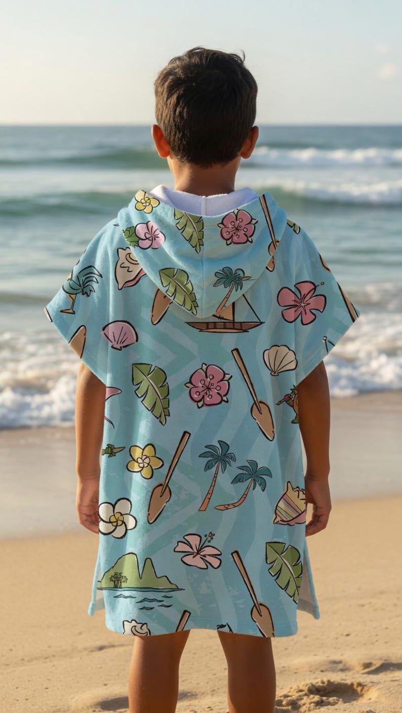 May include: A light blue hooded poncho towel featuring a repeating tropical pattern of pink hibiscus flowers, yellow plumeria, green palm leaves, brown wooden paddles, sailboats, seashells, and small island landscapes with a white interior lining.
