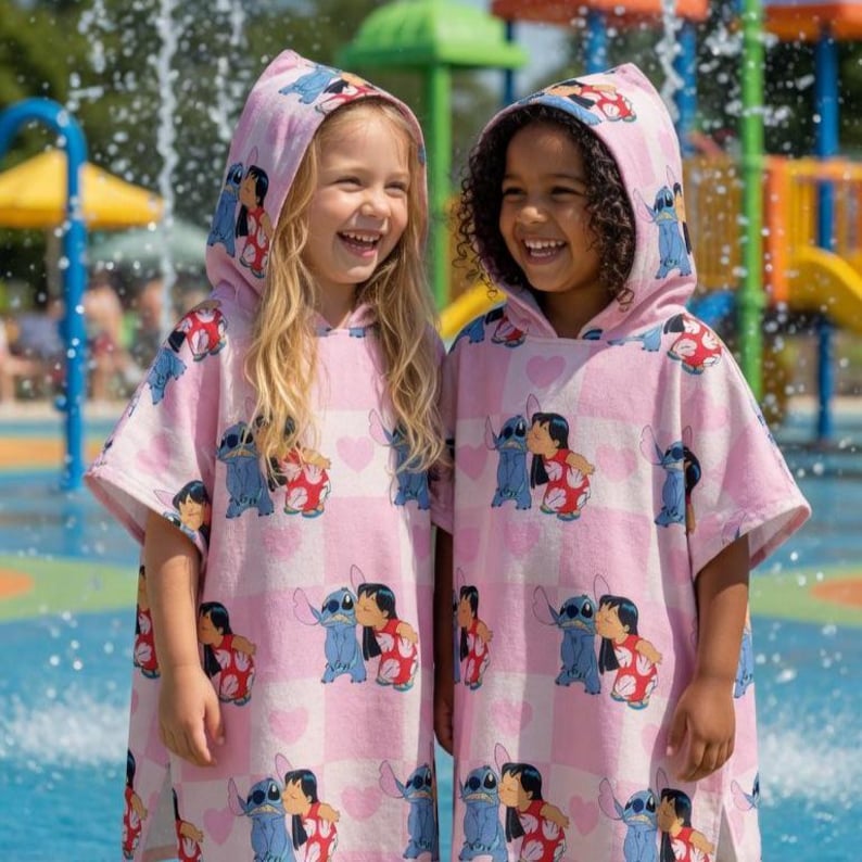 May include: Two hooded poncho towels featuring a repeating pattern of the character Stitch and Lilo on a light pink and white checkered background with small heart shapes. The towels have short sleeves and a loose fit, designed for water activities.