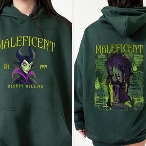 May include: Dark green hoodie with the word "MALEFICENT" in yellow, and a graphic of the Disney villain. The front design includes "EST. 1959" and "DISNEY VILLIAN". The back displays a larger graphic of Maleficent with text.