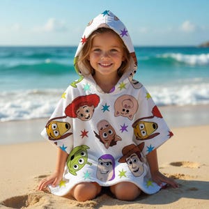 May include: White hooded beach towel featuring colorful cartoon character faces and star accents. The towel is designed for children and is perfect for use at the beach or pool. The towel is made of soft, absorbent material.