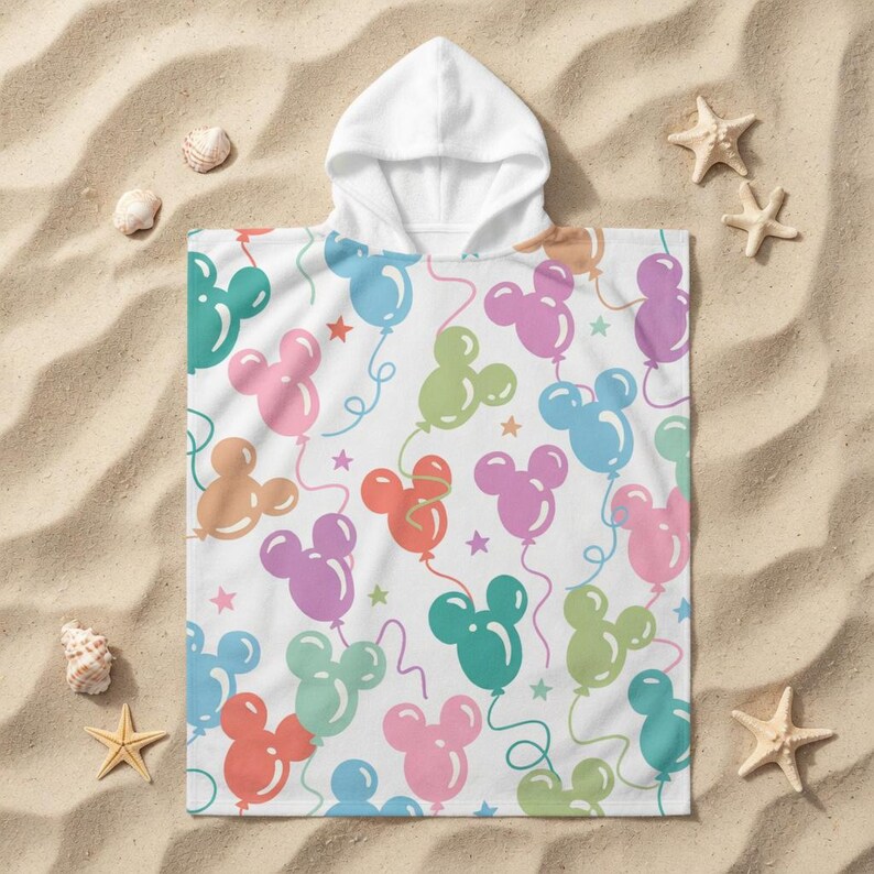 May include: White hooded beach towel featuring a pattern of Mickey Mouse-shaped balloons in shades of pink, blue, green, and orange. The towel is decorated with red stars and curly balloon strings.