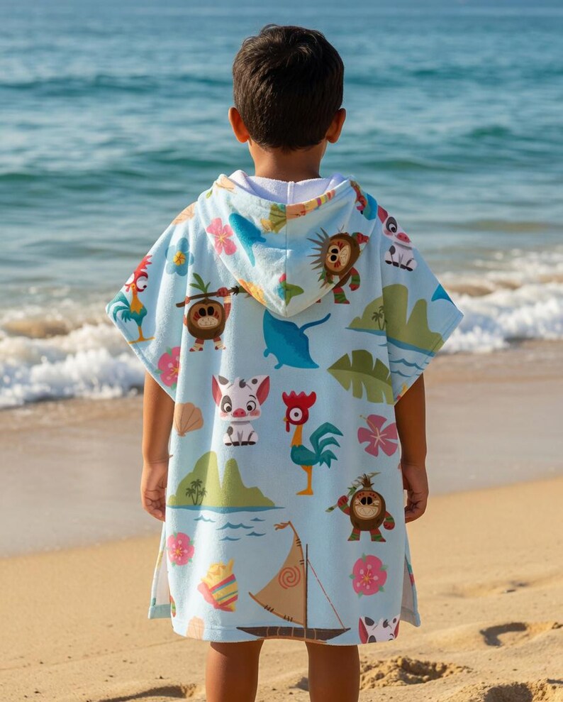 May include: A light blue hooded poncho towel featuring a repeating pattern of cartoon characters, including a rooster, a pig, and small coconut creatures, alongside tropical flowers, green islands, seashells, and a small wooden sailboat.
