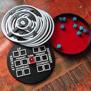 Puede incluir: Un juego de mesa con fichas circulares blancas y negras, una bandeja de dados con dados turquesa y una ficha negra con texto blanco. La bandeja de dados tiene un interior de fieltro rojo. Las fichas tienen un diseño de calavera.