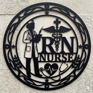 Könnte beinhalten: Schwarzes Metallschild mit der Aufschrift RN Nurse. Das Design zeigt eine Krankenschwester-Silhouette, die einen Klemmbrett und eine Spritze hält, mit den Buchstaben "RN NURSE" in fetter Schrift. Ein Caduceus, ein Herzschlag und ein Stethoskop sind ebenfalls enthalten. Das Schild ist kreisförmig mit dekorativen Rändern.