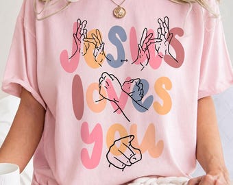 Camiseta "Jesús te ama", camiseta cristiana coqueta, ropa gráfica con temática religiosa.