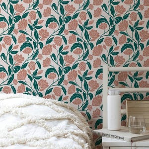 May include: Floral wallpaper featuring a repeating pattern of pink flowers and green leaves on a cream background. The image shows a bed with a white comforter and a nightstand with a water bottle, books, and a glass of water.