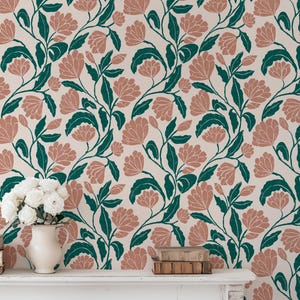 May include: Floral wallpaper featuring a repeating pattern of stylized pink flowers and dark green leaves on a cream background. The design has a vintage aesthetic, suitable for home decor. A white vase with white flowers and books are on a white mantel.