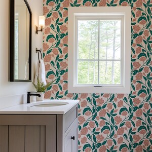 May include: A bathroom with floral wallpaper featuring pink flowers and green leaves on a cream background. The room includes a gray vanity with a white countertop, a mirror, and a window with a view of trees.