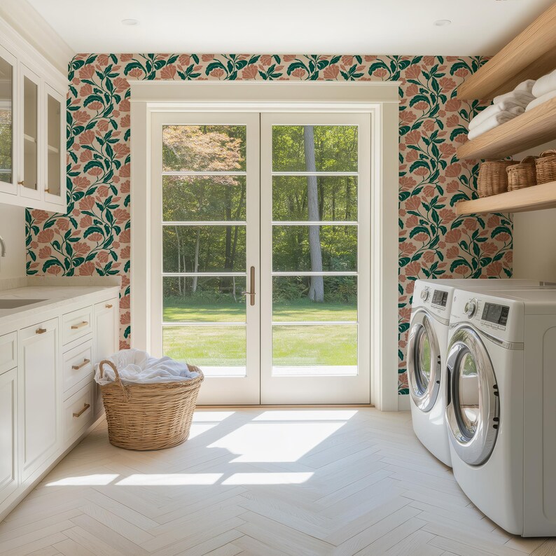 May include: A bright, airy laundry room with white cabinets, a washing machine, and a dryer. A large wicker basket holds folded white towels. The walls are decorated with a floral pattern in shades of pink, green, and beige.