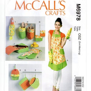 May include: McCall's Crafts pattern M6978 featuring a variety of kitchen accessories. The pattern includes an apron, oven mitts, pot holders, utensil holders, and a bread basket. The accessories have a citrus fruit design with orange, green, and white colors.
