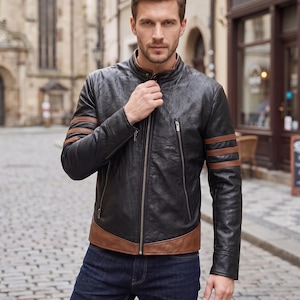 May include: A black leather jacket featuring a stand-up collar, a full-length front zipper, and two vertical zippered chest pockets. The sleeves are accented with three horizontal brown leather stripes, and the hem is finished with a brown leather band.