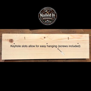 May include: A wooden sign with the text "Keyhole slots allow for easy hanging (screws included)". The sign has keyhole slots for hanging and a "Nailed It Woodworks" logo.