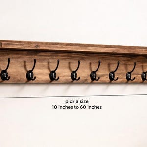 May include: A wooden wall-mounted coat rack with eight black metal hooks. The rack has a shelf and is 9.25 inches high and 5 inches deep. The length can be selected from 10 inches to 60 inches. The wood has a natural finish.