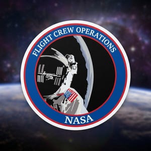 May include: A circular NASA Flight Crew Operations patch featuring a stylized astronaut, the International Space Station, and the American flag. The patch has a blue and red border with the words "FLIGHT CREW OPERATIONS" and "NASA". The background shows a view of Earth and space.