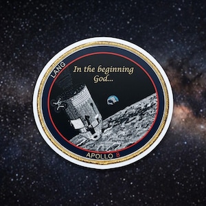May include: Circular patch with a gold border, featuring an illustration of the Apollo 8 spacecraft on the moon. The text "In the beginning God..." and "APOLLO 8" are visible. The background is a starry night sky.