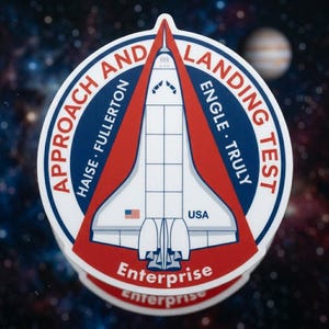 May include: A circular sticker featuring a white space shuttle in the center with red and blue borders. The text reads APPROACH AND LANDING TEST, HAISE, FULLERTON, ENGLE, TRULY, USA, and Enterprise. A small American flag is visible on the shuttle.