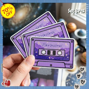 May include: Set of three purple cassette tape stickers with the word "Mikrokosmos" in a whimsical font. The stickers have a retro design with a starry sky and cloud background. The stickers are held in a hand.