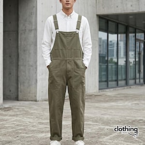 May include: Olive green dungarees with adjustable straps, worn over a white shirt. The overalls have multiple pockets and are paired with white trainers. The image is set against a modern architectural backdrop.