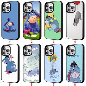 May include: A selection of eight phone cases, each with a black border, depicting Eeyore from Winnie the Pooh. The cases feature Eeyore in various scenes and poses, with backgrounds in blue, green, and white. The cases are designed for a mobile phone.